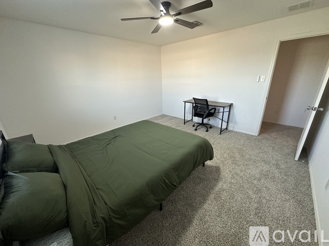 A bedroom with a bed, chair, and ceiling fan.
