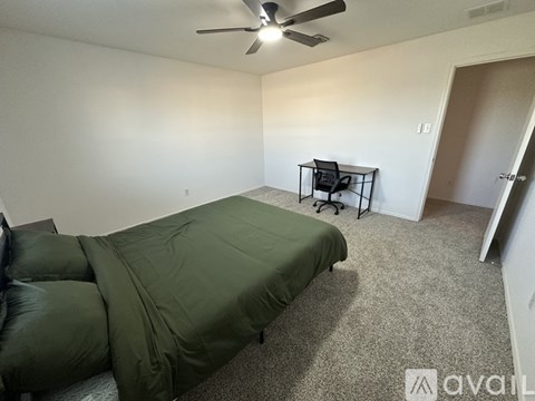 A bedroom with a bed, chair, and ceiling fan.