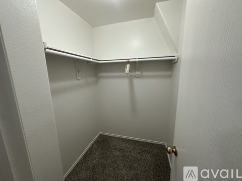 A small, empty closet with a carpeted floor and a single coat hanger.