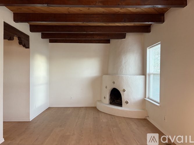 A room with a fireplace and wooden beams on the ceiling.