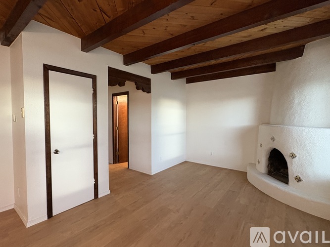 A room with a fireplace and wooden beams on the ceiling.