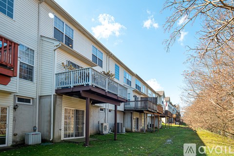 A row of apartment buildings with balconies and a grassy area in front.