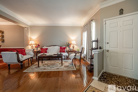 A living room with a couch, chairs, and a rug.