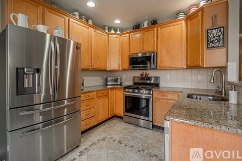 A kitchen with wooden cabinets and a stainless steel refrigerator.