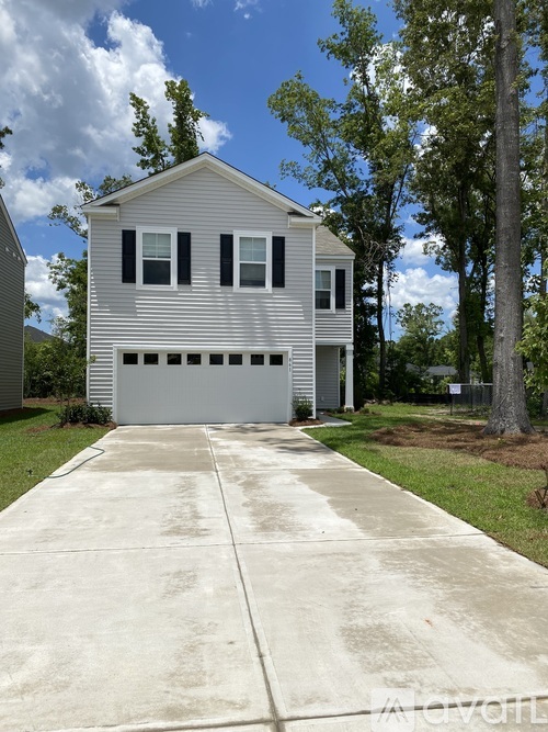 A two-story house with a garage is surrounded by trees.