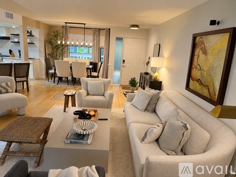 A living room with a large couch, a coffee table, and a painting on the wall.