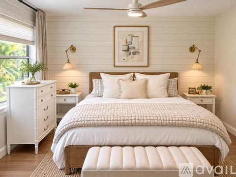A bedroom with a large bed, a dresser, and a window with curtains.
