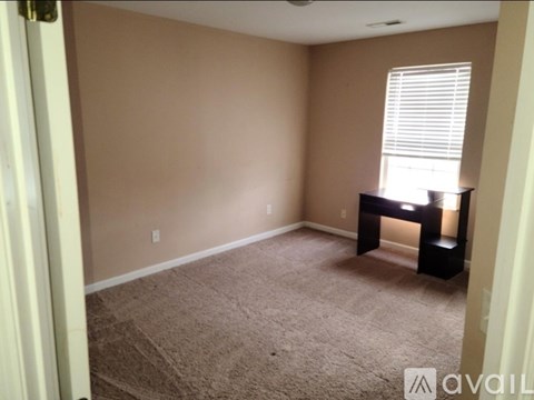 A room with a carpeted floor and a desk with a lamp.