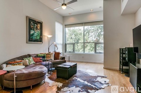 A living room with a brown couch and a cowhide rug.