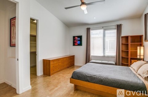 A bedroom with a bed, dresser, and a ceiling fan.