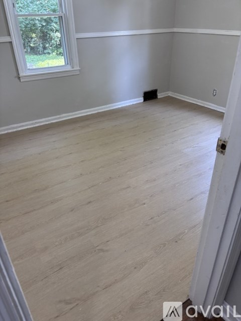 A room with a window and wooden flooring.