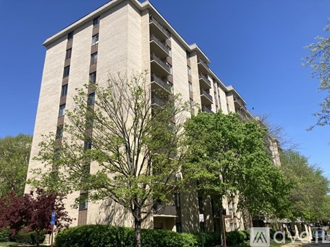 A tall beige building with a tree in front of it.