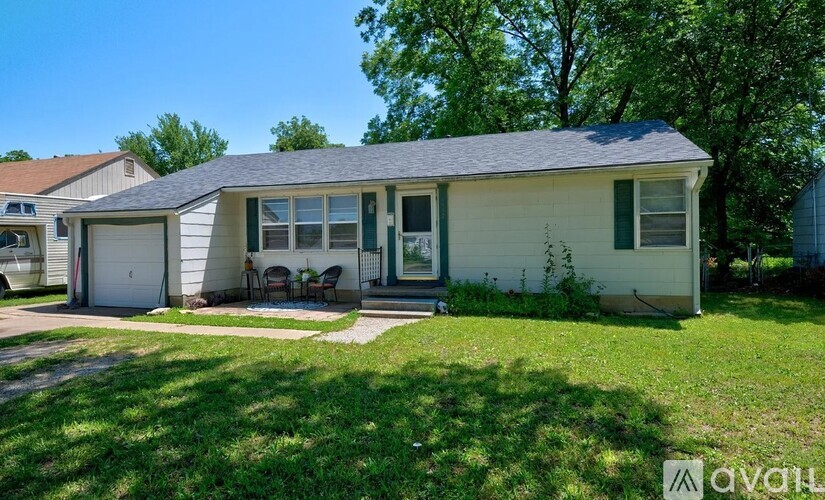 A house with a green lawn and trees in the background.