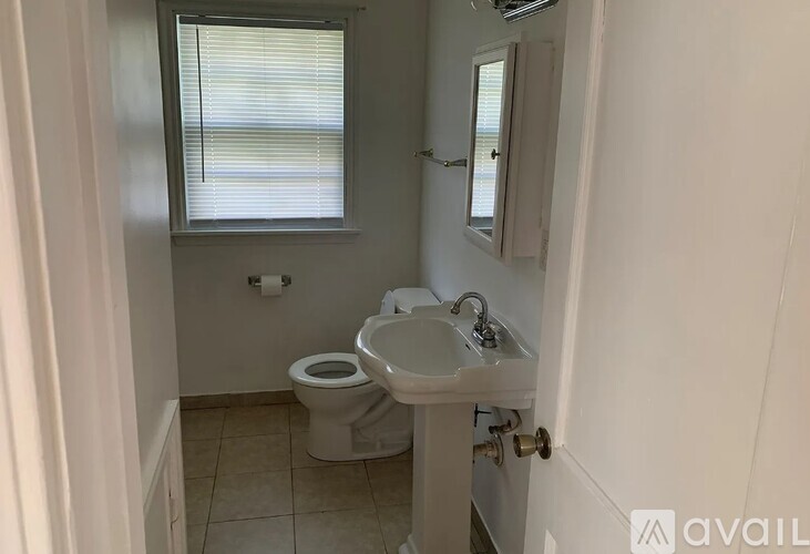 A bathroom with a toilet, sink, and window.