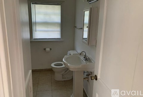 A bathroom with a toilet, sink, and window.