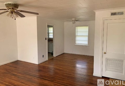A room with a ceiling fan and wooden floors.