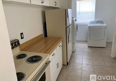 A kitchen with white appliances and a wooden countertop.