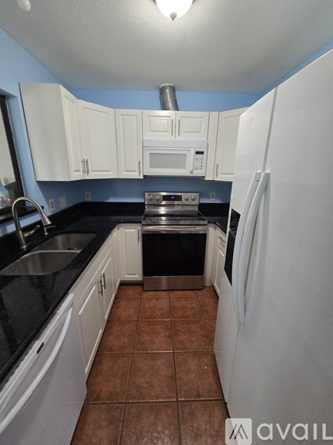 A kitchen with white cabinets and a black counter top.