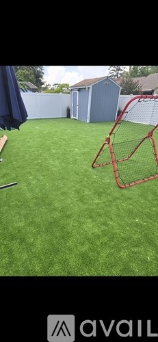 A backyard with a green lawn and a red goal post.