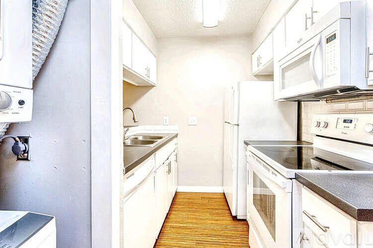 A kitchen with white appliances and wooden floors.