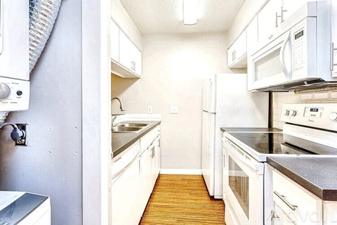 A kitchen with white appliances and wooden floors.