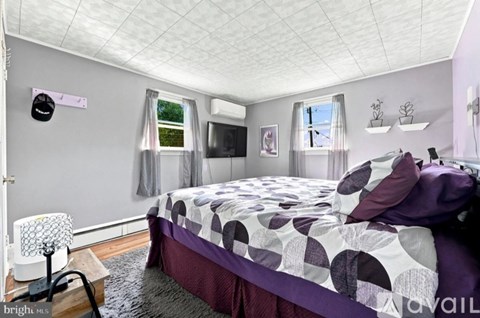 A bedroom with a bed, a chair, and a window.