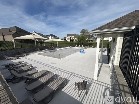 A pool area with sun loungers and a fence.