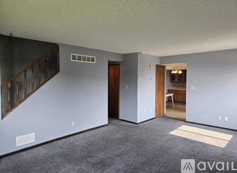A room with a carpeted floor and a staircase with wooden railings.