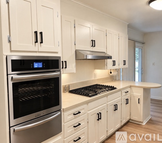 A modern kitchen with white cabinets and stainless steel appliances.