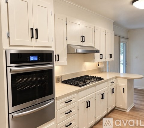 A modern kitchen with white cabinets and stainless steel appliances.