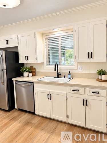 A kitchen with white cabinets and a black fridge.