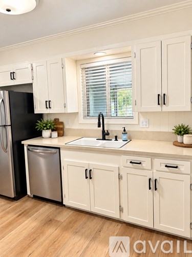 A kitchen with white cabinets and a black fridge.