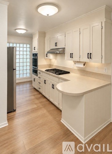 A kitchen with white cabinets and a wooden floor.