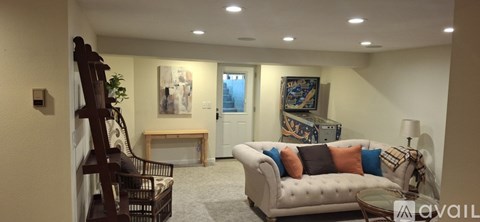 A living room with a white couch and a wooden chair.