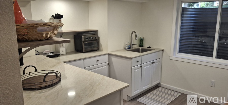 A kitchen with white cabinets and a marble countertop.