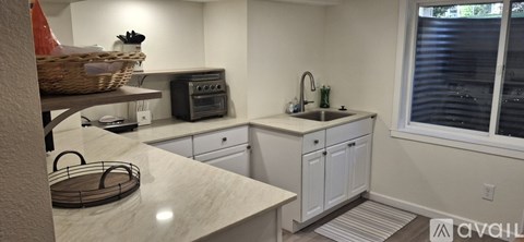 A kitchen with white cabinets and a marble countertop.