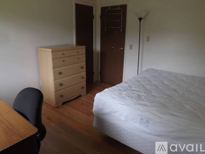 A bedroom with a bed, desk, chair, and dresser.