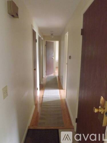 A hallway with a door on the right and a light switch on the wall.