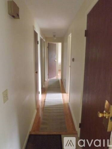 A hallway with a door on the right and a light switch on the wall.