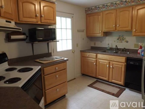 A kitchen with wooden cabinets and a black microwave.