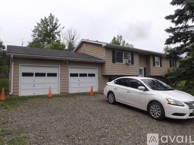 A white car is parked in front of a two-car garage.