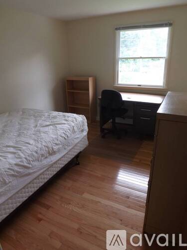 A bedroom with a bed, desk, and chair.