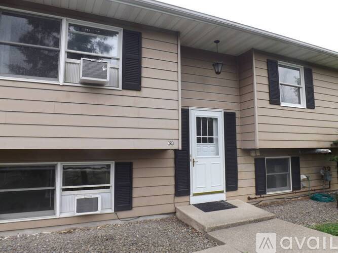 A house with a white door and black shutters is for sale.