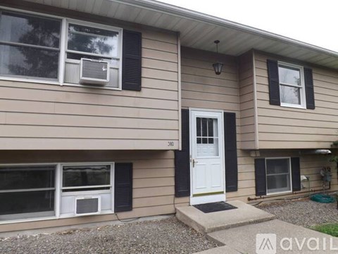 A house with a white door and black shutters is for sale.