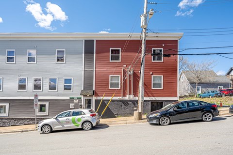 Two cars parked in front of a red building.