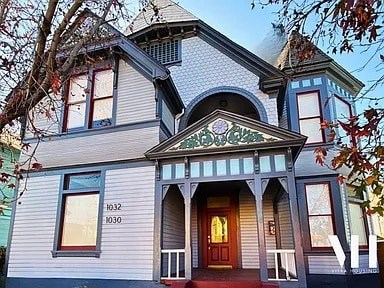 A Victorian style house with a red door and a window with the number 1030 on it.
