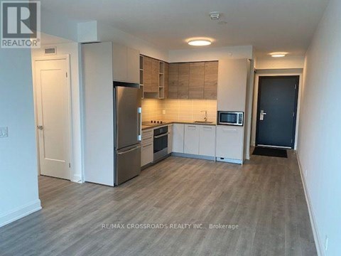 A kitchen with a refrigerator, oven, and microwave.