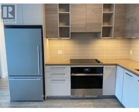 A kitchen with a refrigerator, oven, and cabinets.