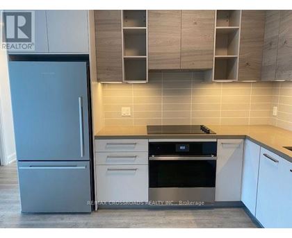 A kitchen with a refrigerator, oven, and cabinets.