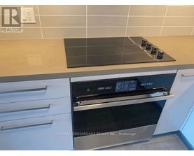 A modern kitchen with a stove top oven and a tile backsplash.